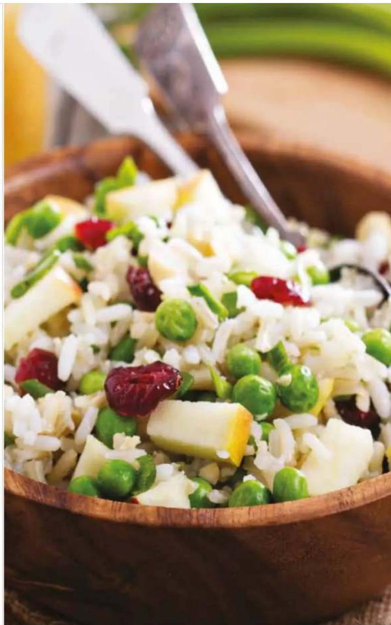 Close-up of a wooden bowl containing a colorful salad with rice, peas, and red berries (no text or symbols visible)