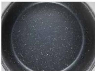 Close-up of a dark, circular bowl containing fine granular substance (no text or symbols visible)