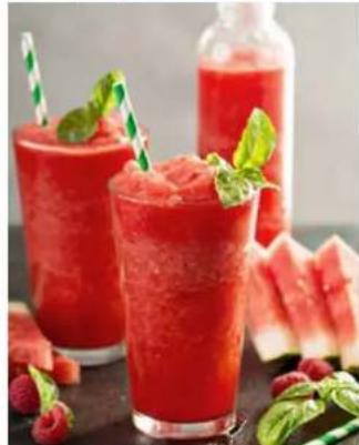 Two red beverage glasses with mint garnishes, surrounded by watermelon slices and a bottle of juice (no text or symbols visible)