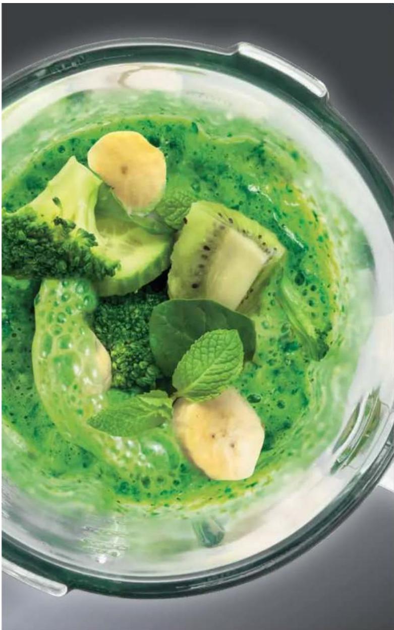 Top-down view of a green vegetable soup in a clear glass bowl, featuring broccoli, kiwi mushrooms, and mint leaves (no text or symbols visible)