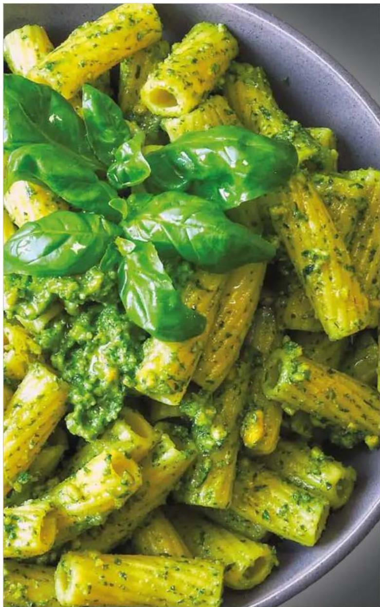 Close-up of a pasta dish with green broccoli and fresh cilantro leaves in a bowl (no text or symbols visible)