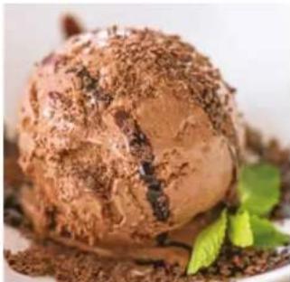 Close-up of a chocolate ice cream with mint leaves, served on a white plate (no text or symbols visible)