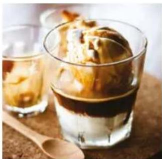 Glass of layered dessert with ice cream and a wooden spoon on a wooden surface (no text or symbols visible)