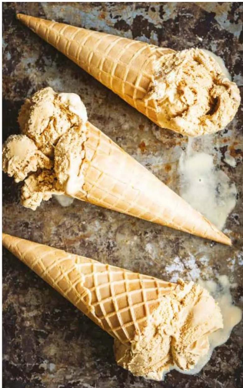Three ice cream cones on a textured surface, one being cut with ice cream and the other holding ice cream (no text or symbols visible)