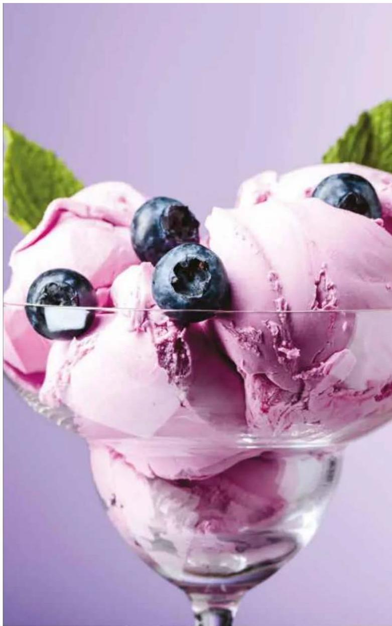 Close-up of a glass ice cream with pink ice cream and blueberries, garnished with green leaves against a purple background (no text or symbols)