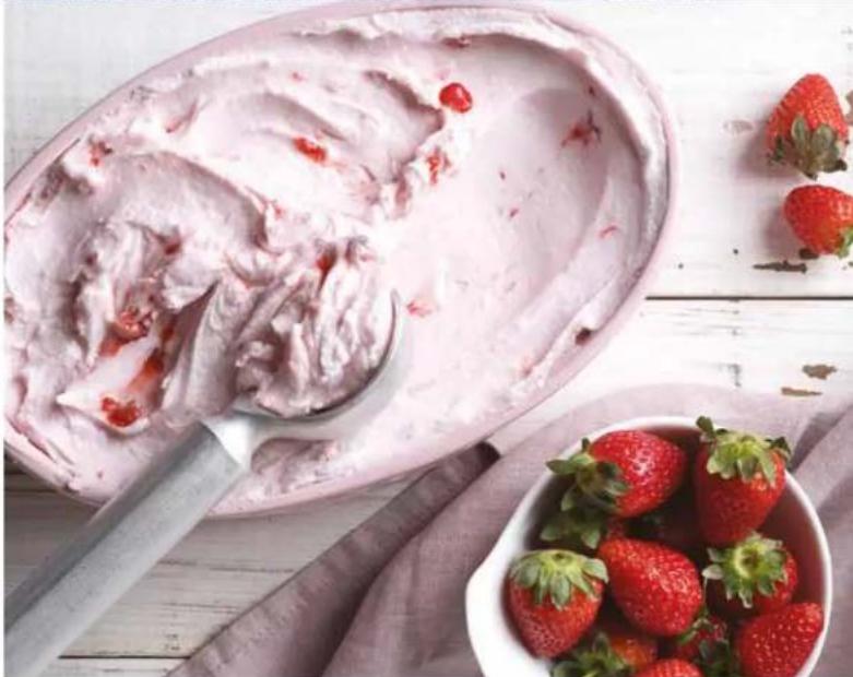 Close-up of a pink ice cream with strawberry topping and fresh strawberries in a bowl on a wooden tablecloth (no text or symbols visible)