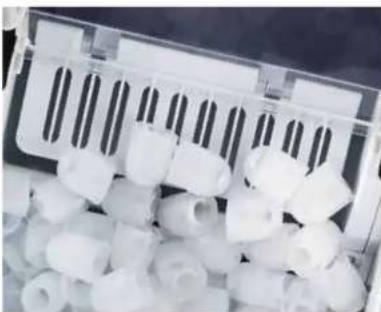 Close-up of white plastic cylindrical objects arranged in a container (no visible text or symbols)