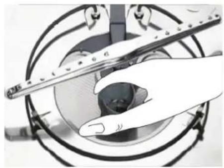 Close-up of a hand using a tool to adjust or install a circular component, no visible text or symbols