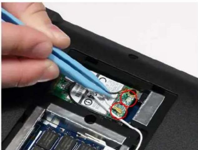 Close-up of a hand using a blue tool to clean or repair a circuit board with visible traces and components.