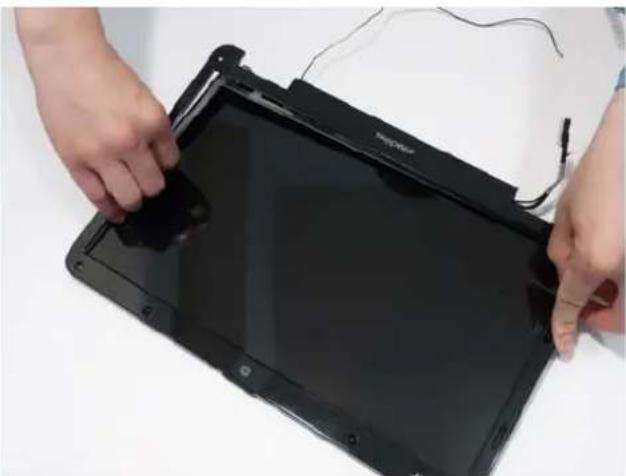 Close-up of hands installing or adjusting a black electronic device with a cable. No visible text or symbols.