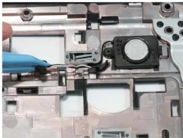 Close-up of a laptop's internal components with a gloved hand adjusting cable (no visible text or symbols).