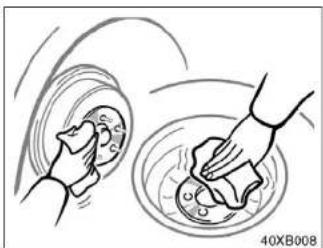 Illustration of a hand cleaning a circular object with a cloth, no text or symbols present