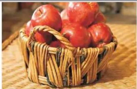 Basket filled with fresh red apples, placed on a woven mat (no text or symbols visible)