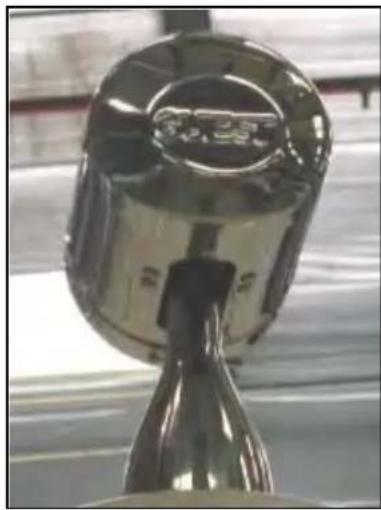 Close-up of a metallic mechanical component with a handle and spout, no visible text or symbols