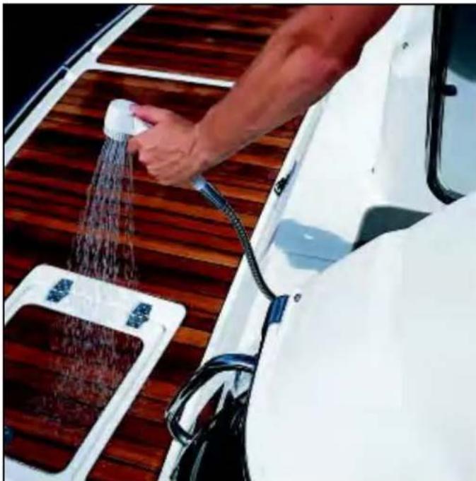Person using a showerhead to spray water from a wooden boat on a wooden deck (no text or symbols visible)