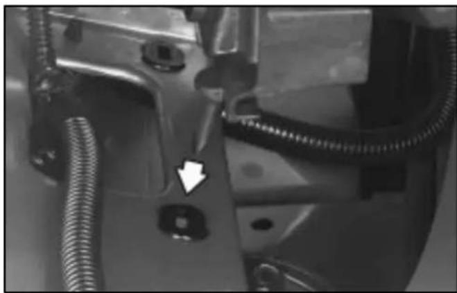Close-up of a mechanical component with coiled tubing and a white arrow pointing to a small square feature (no visible text or symbols)