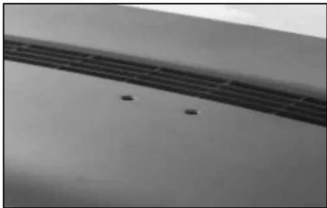 Close-up of a metallic surface with parallel grooves and small dark spots (no text or symbols visible)
