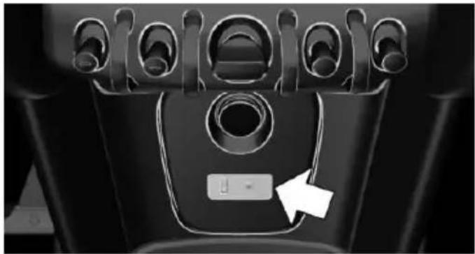 Close-up of a car interior showing a black seat with multiple circular switches and a white button labeled 'L' pointing to it (no text or symbols beyond the button)