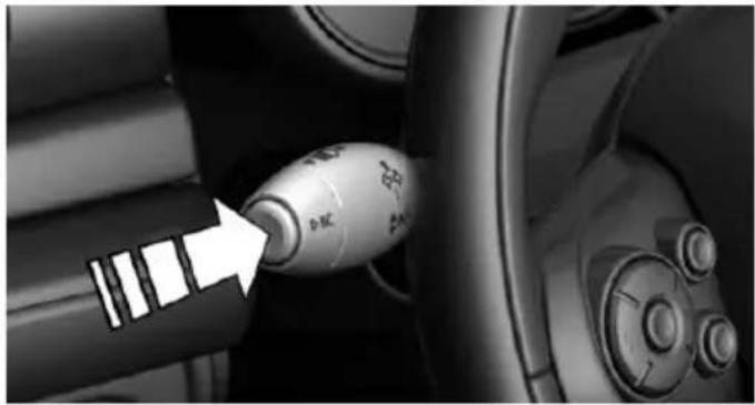 Close-up of a car's internal gear shift lever with a white arrow pointing to the component (no text or symbols visible)