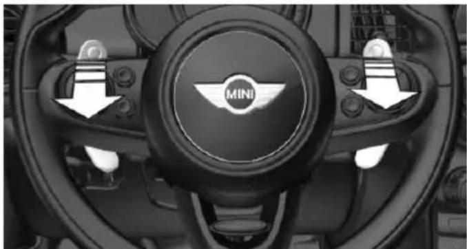 Interior view of a car dashboard with the Mini wheel and directional arrows indicating steering control (no text or symbols beyond branding)