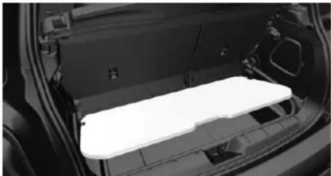 Interior view of a car showing the rear compartment of a vehicle with a white plastic tray (no text or symbols visible)