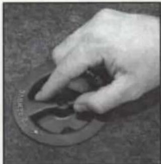 Close-up of a hand pressing down on a circular mechanical component (no visible text or symbols)