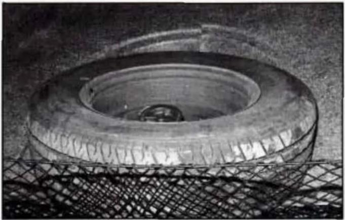 Close-up of a car tire mounted on a mesh metal frame (no visible text or symbols)
