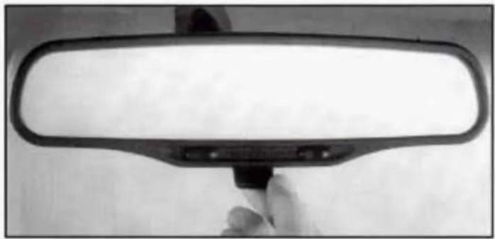 Close-up of a car rear view mirror with a hand holding the rim (no text or symbols visible)