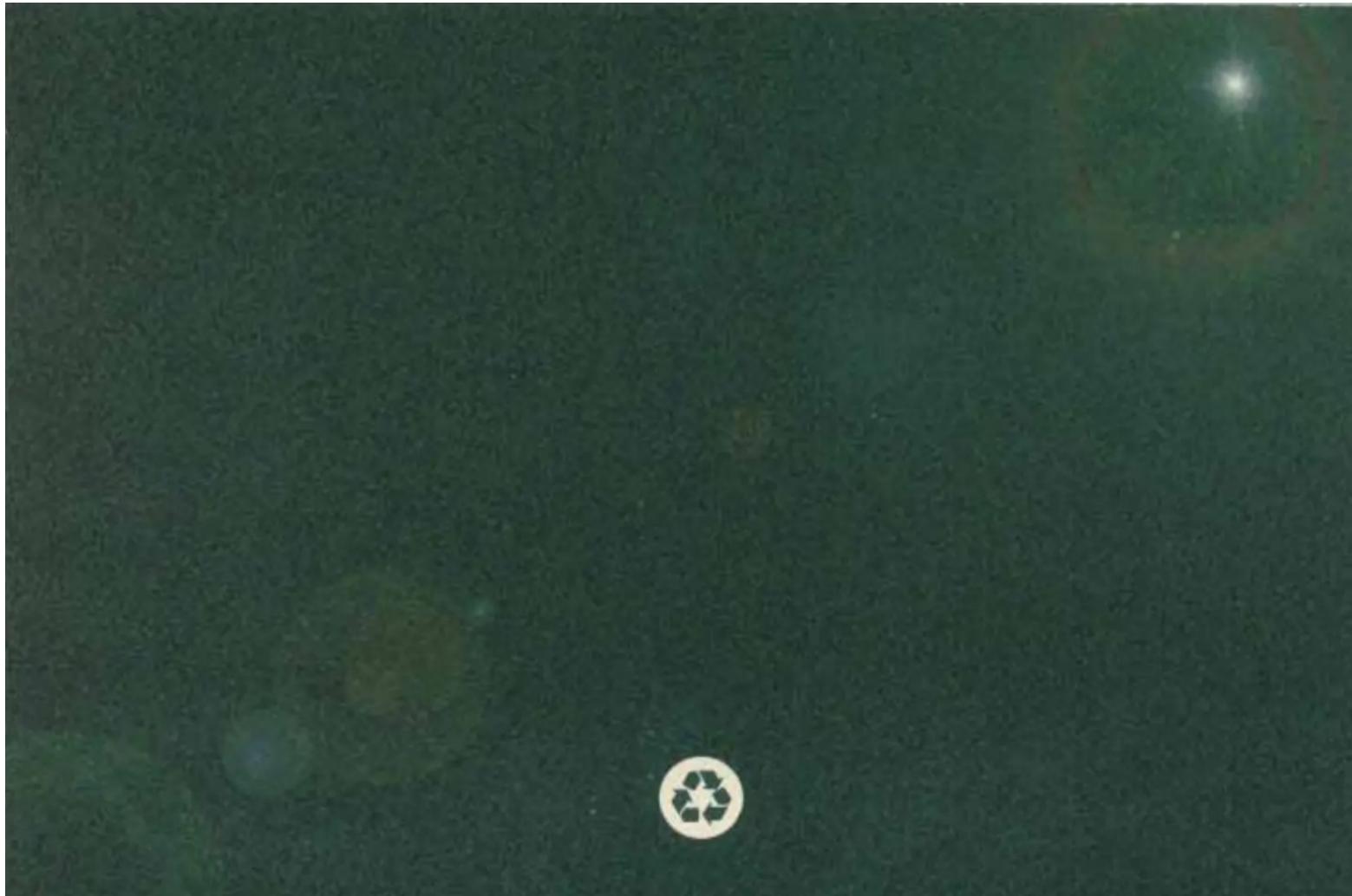 Dark green textured surface with a white circular logo containing a recycling symbol (no text or symbols present)