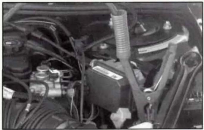 Close-up of an automotive engine bay with visible hoses, springs, and battery (no text or symbols)