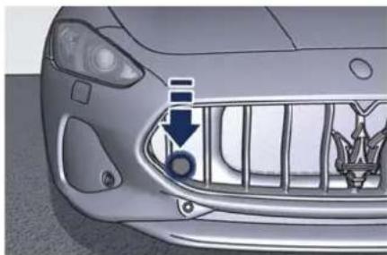 Close-up of a car's front grille with a blue arrow pointing to a circular symbol (no text or labels visible)