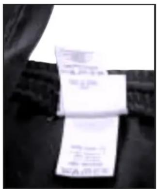 Black-and-white photo of folded clothing with visible text on a piece, likely a garment or fabric sample.