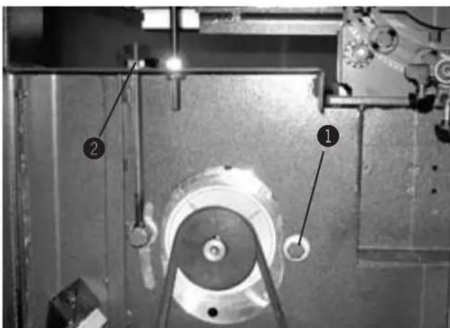 Technical diagram of a mechanical assembly with labeled parts 1 and 2, showing components like pulleys and gears.