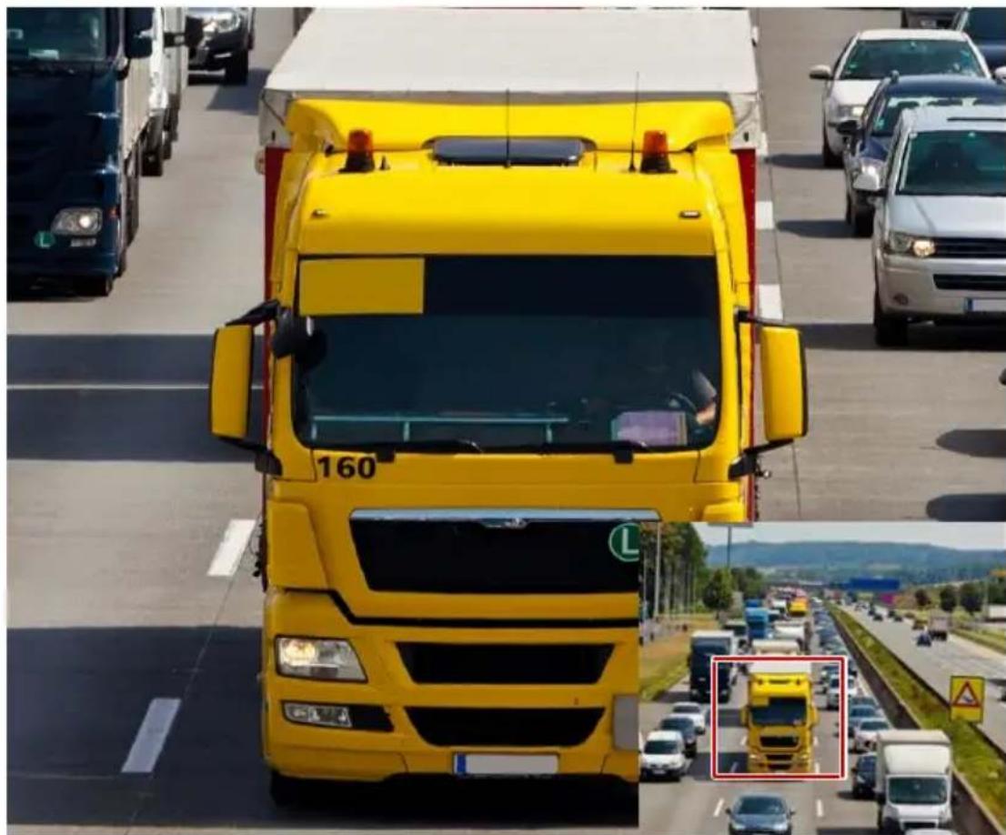 Yellow heavy-duty truck driving on a multi-lane highway, with traffic and a red inset showing a vehicle (no visible text or symbols)