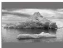 Black-and-white photo of a rocky outcrop floating on calm water, no visible text or symbols