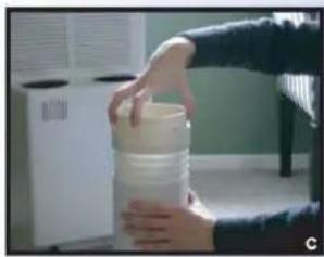 Person holding a white plastic container with a hand extending from it, in an indoor setting (no visible text or symbols)