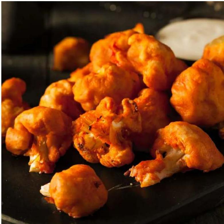 Close-up of golden-brown fried food items on a dark surface, possibly peaches or pizza (no text or symbols visible)
