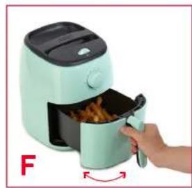Hand placing a cooking pan into an air fryer with food being processed (no text or symbols visible)