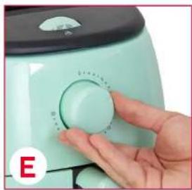 Close-up of a hand pressing down on a light green air fryer (no visible text or symbols)