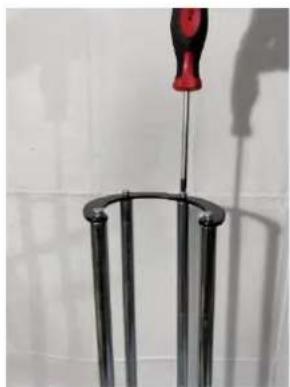 Close-up of a metal stand with a red screwdriver inserted, against a plain white background (no text or symbols visible)