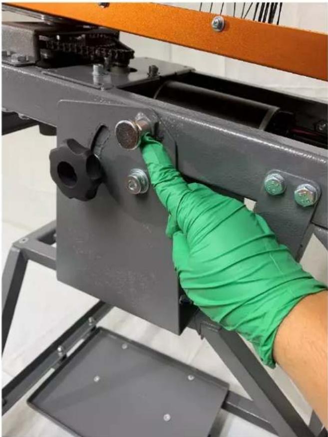 Close-up of a gloved hand installing or adjusting a metal bracket with bolts, no visible text or symbols