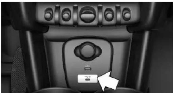 Close-up of a car seat panel with control knobs and a white arrow pointing to a button (no text or symbols visible)