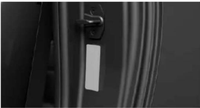 Close-up of a door handle with a white rectangular label, showing black and white photo (no text or symbols visible)