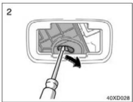 Diagram showing a screwdriver inserted into a component with an arrow indicating direction (no text or symbols present)