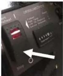 Close-up of a device panel with visible labels and an arrow pointing to a component, likely indicating a measurement or status.