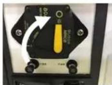 Close-up of an electrical switch panel with a yellow component and directional arrow indicating rotation or change.