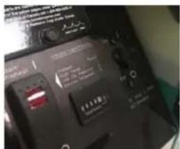 Close-up of a black electronic device with visible control buttons and display screen, showing Chinese text labels.