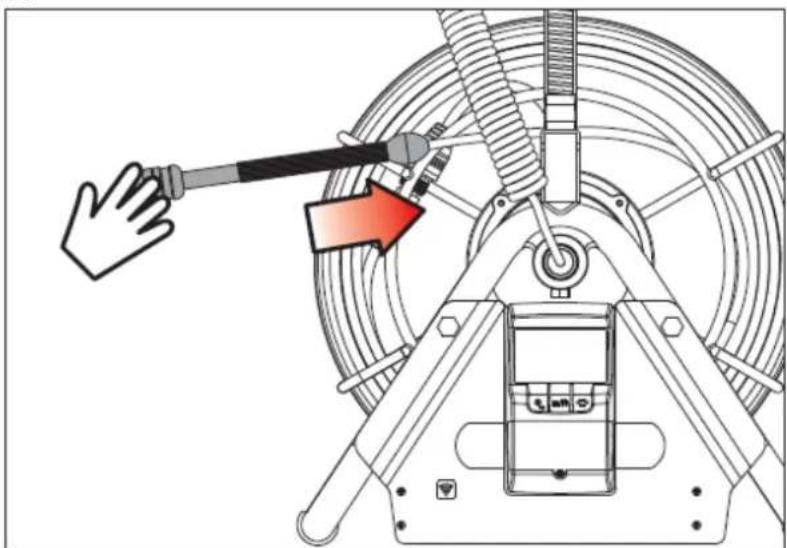 Technical diagram showing a hand operating a cable with a red arrow indicating direction, likely illustrating a mechanical or electrical component.