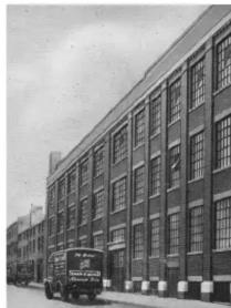 Exterior view of a multi-story industrial building with a vintage truck parked in front (no visible text or signage)