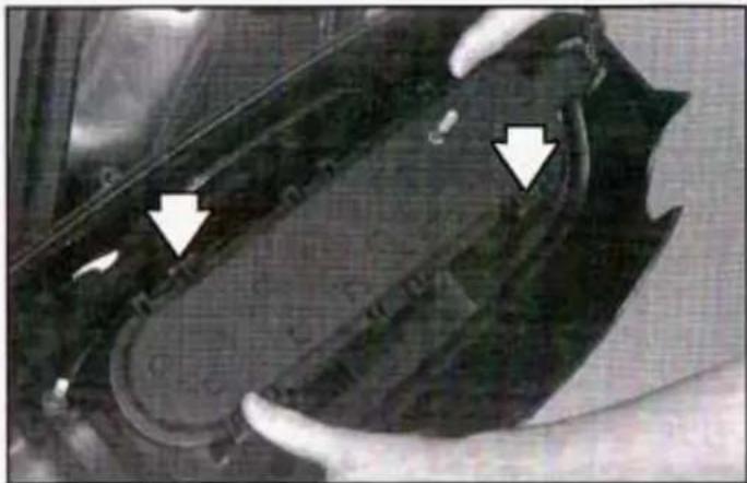 Close-up of a mechanical component with two white arrows pointing to features, no visible text or symbols.